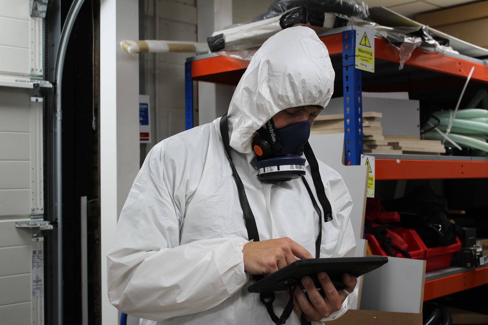 A man in a white hazmat suit is working on a pipe