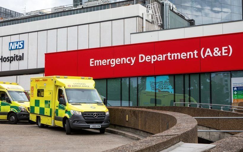 Three ambulances are parked in front of the emergency department of a hospital.