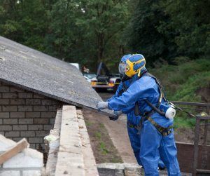A man in a blue suit is working on a roof.