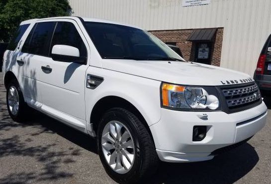 A white land rover freelander is parked in front of a building.