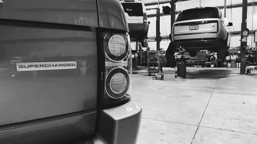 A black and white photo of a range rover being repaired in a garage.