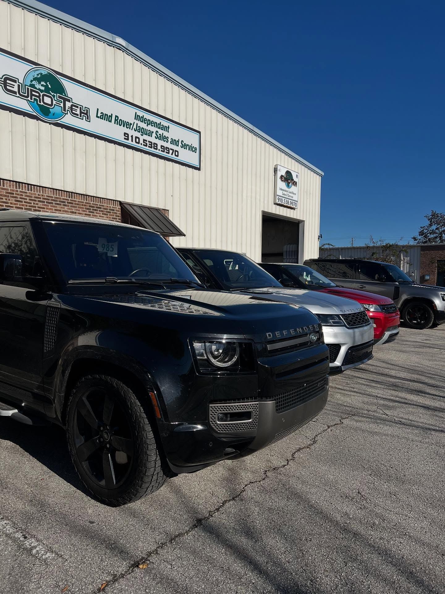 Several luxury SUVs parked in front of a building with a business sign.