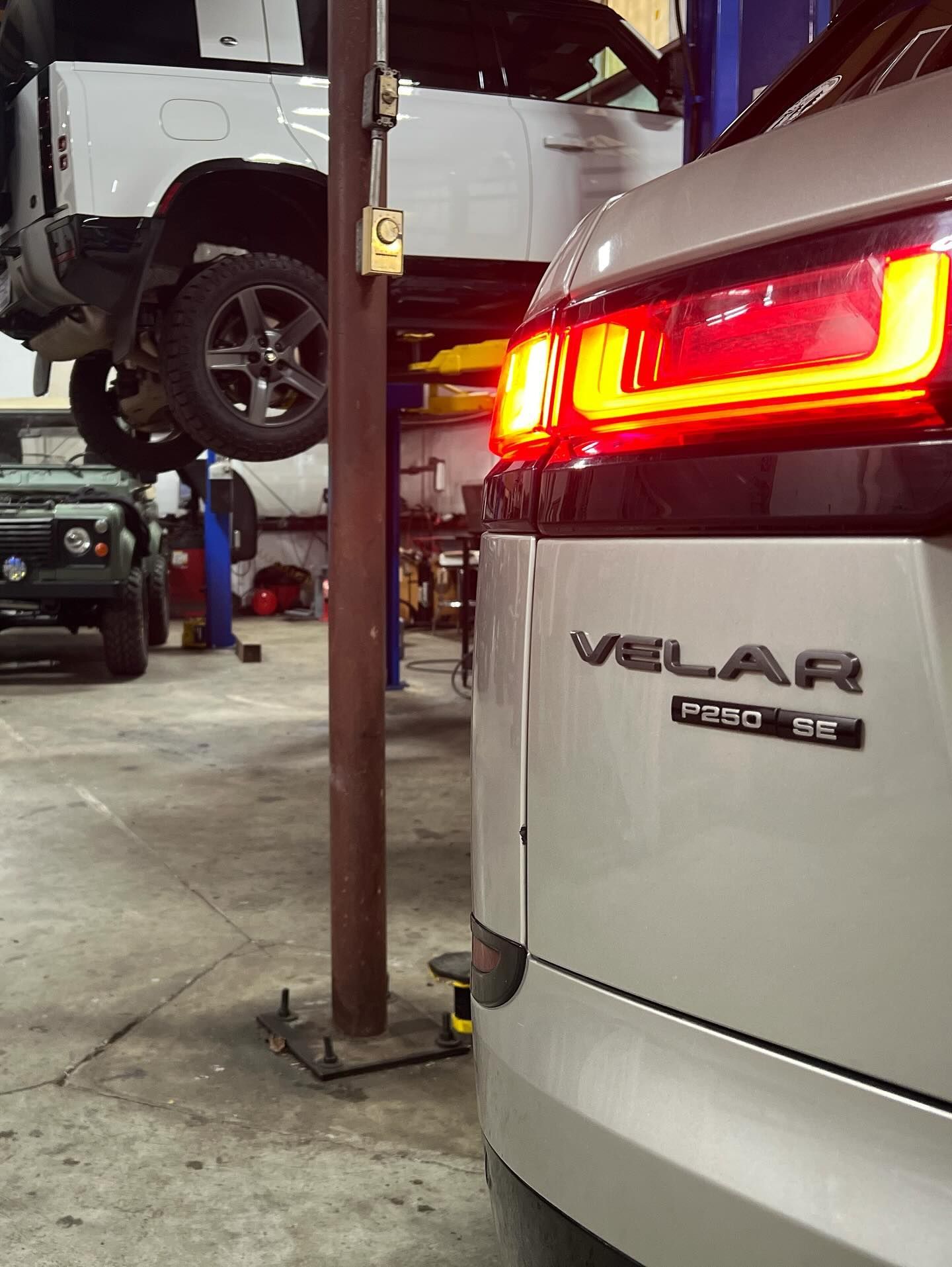 Silver Range Rover Velar in a car repair shop with other vehicles visible.
