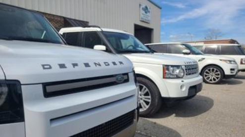 White Land Rover SUVs parked outside a building on a sunny day.