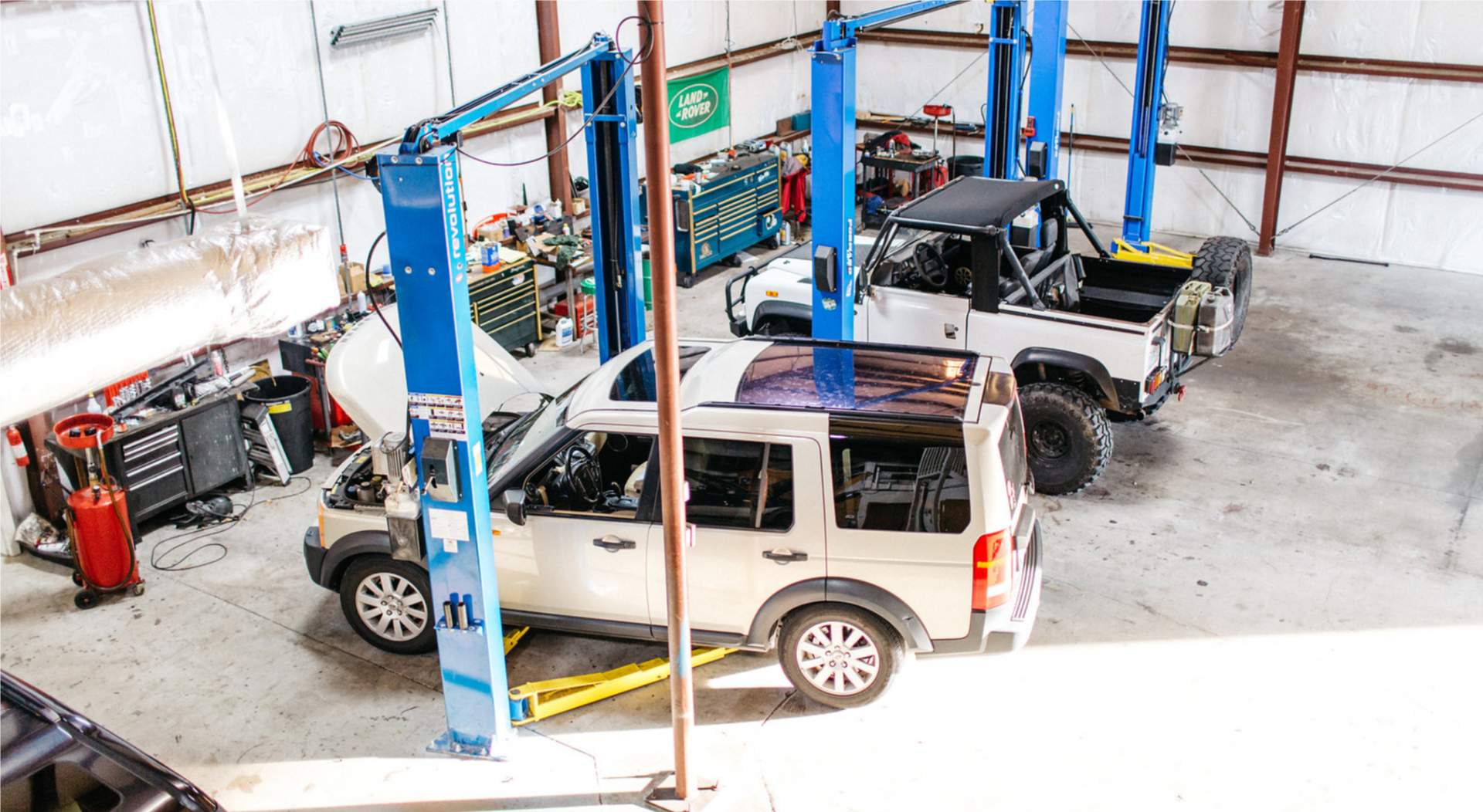 A group of cars are sitting on a lift in a garage.
