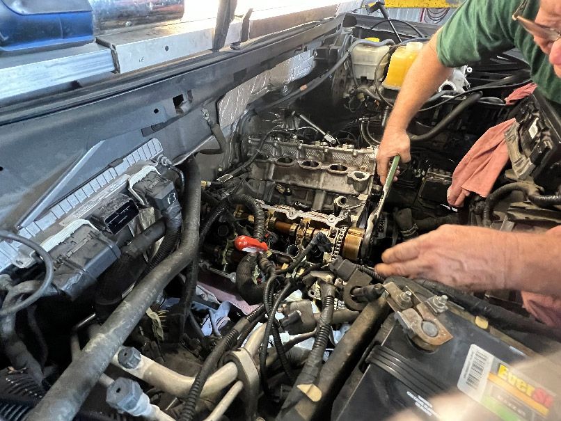 Mechanic working on a car engine in an open hood bay, with tools and exposed components in New Hanover County, NC