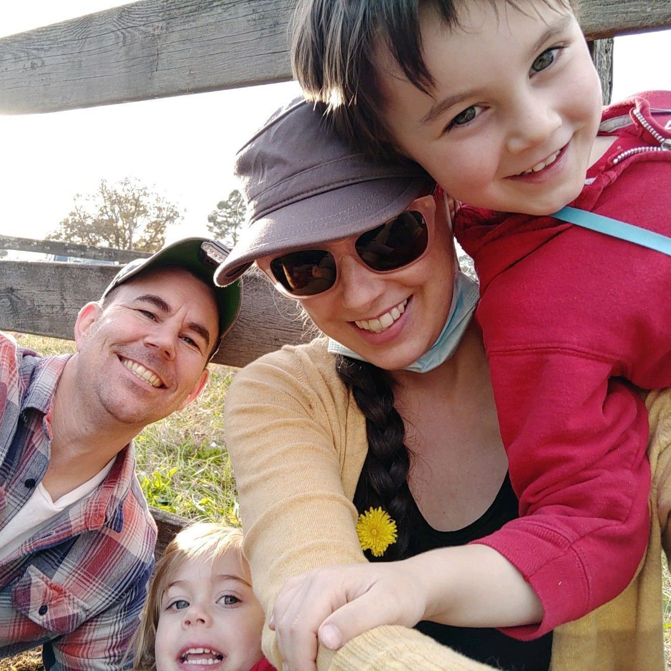 A family is posing for a picture in front of a wooden fence.