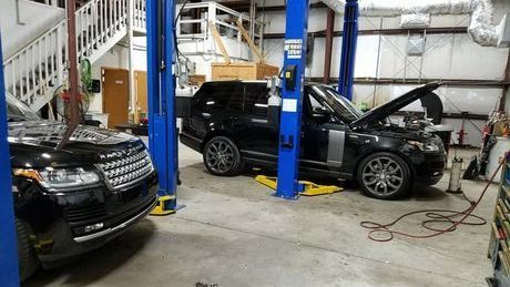A green land rover is on a lift in a garage