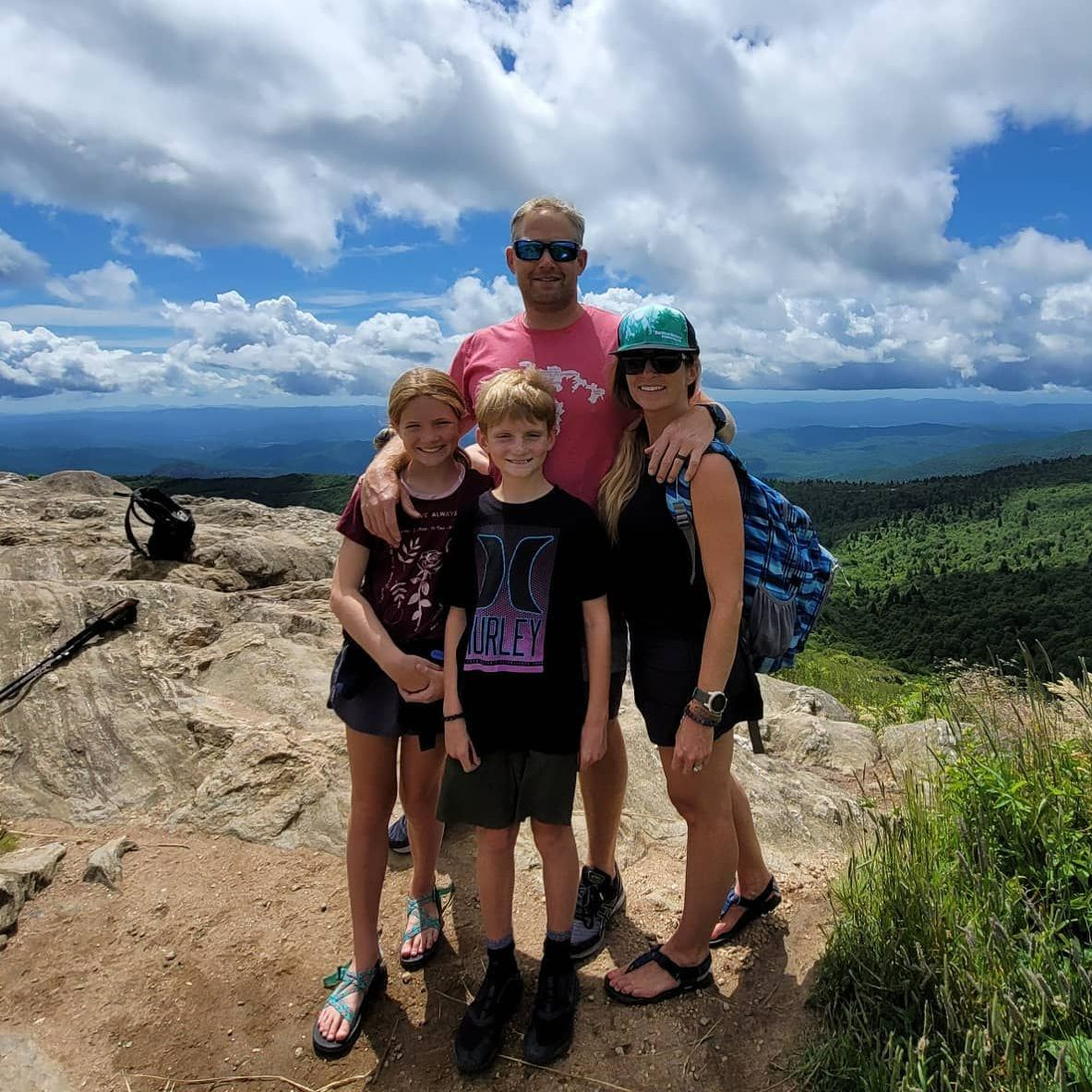 A family is posing for a picture on top of a mountain.
