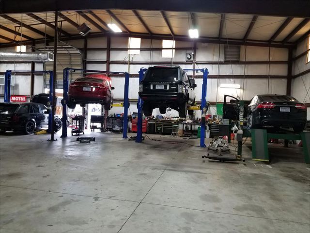 Several cars are sitting on lifts in a garage