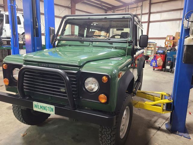 A green land rover is on a lift in a garage