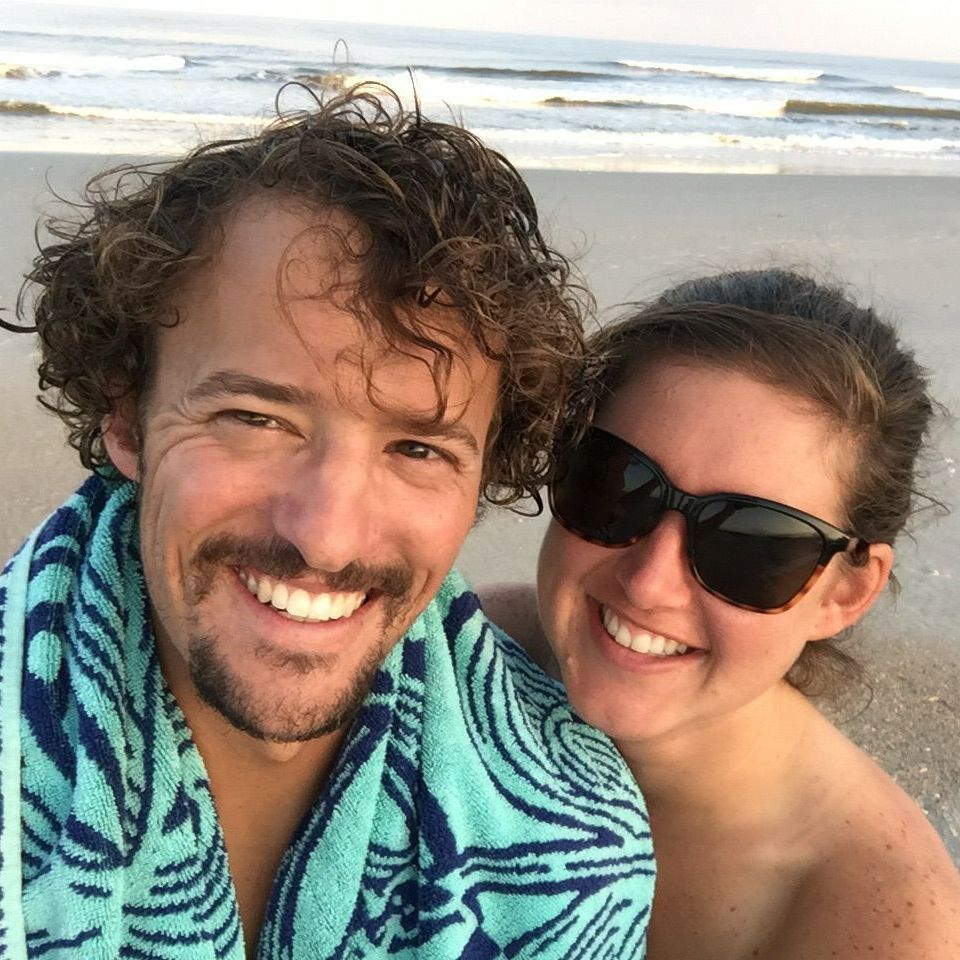 A man and a woman are posing for a picture on the beach