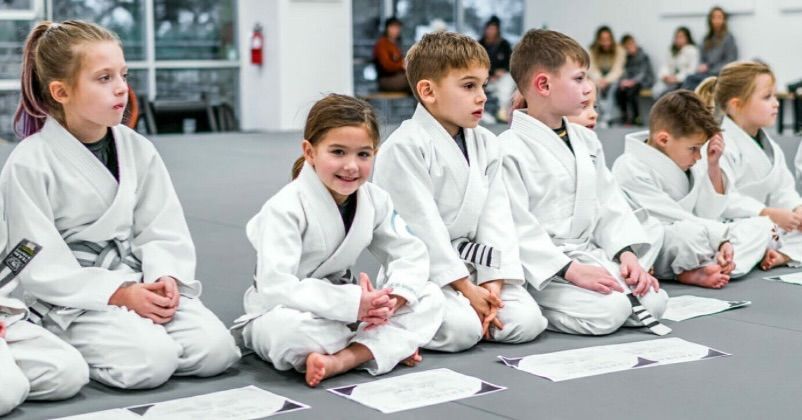 Five men in black gi uniforms, with belts, posing.