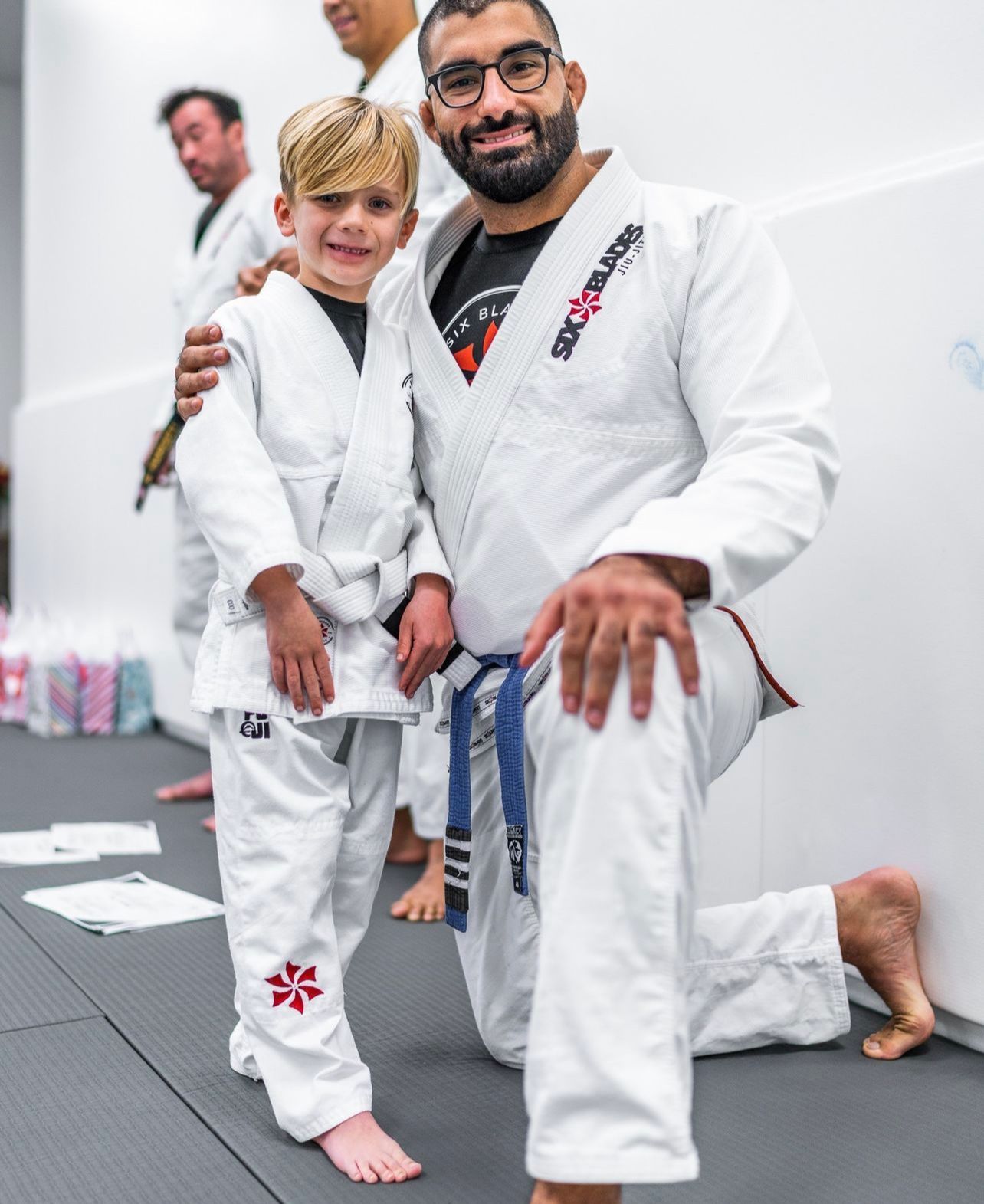 Five men in black gi uniforms, with belts, posing.
