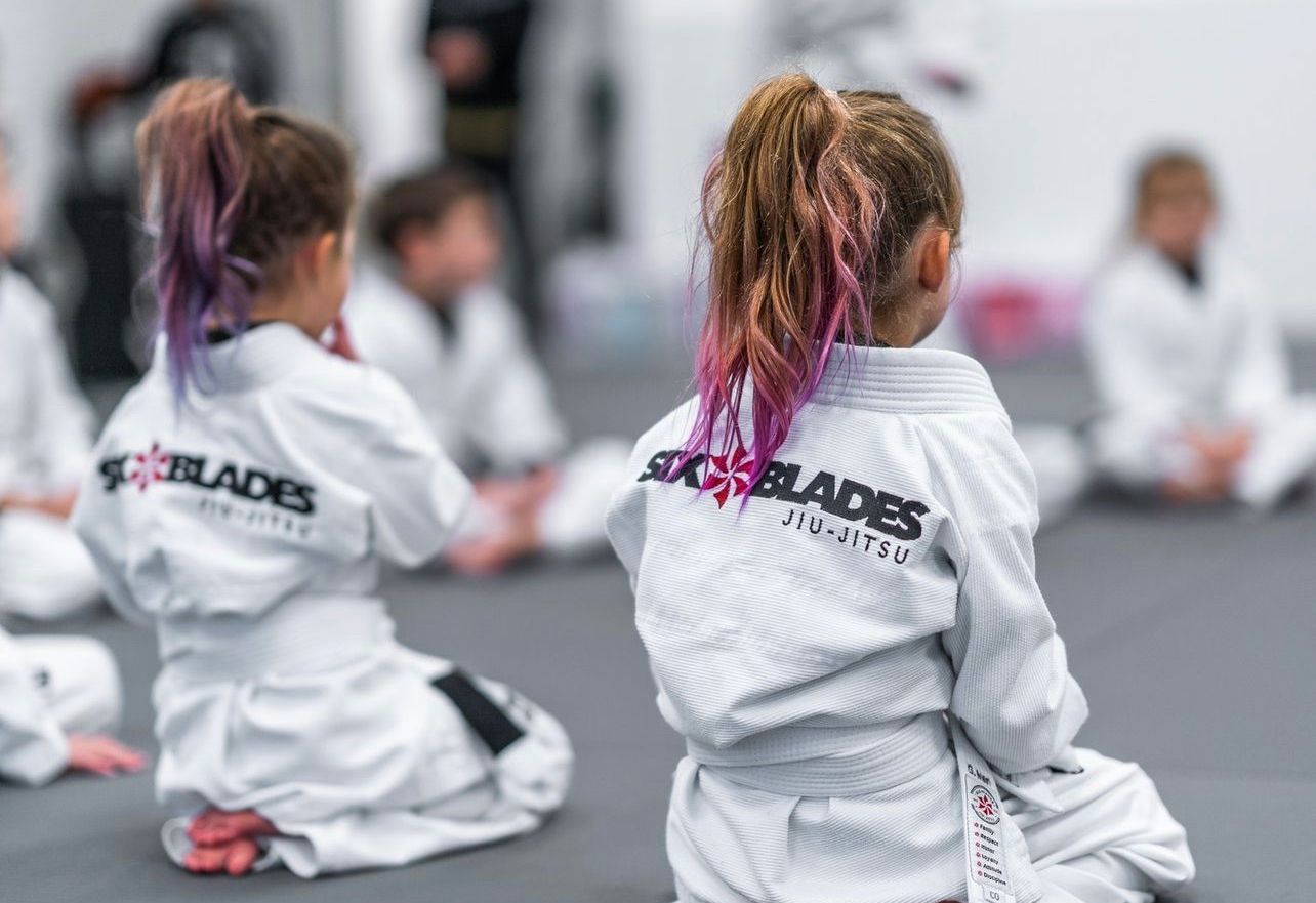Five men in black gi uniforms, with belts, posing.