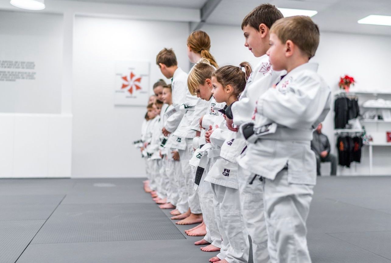 Five men in black gi uniforms, with belts, posing.