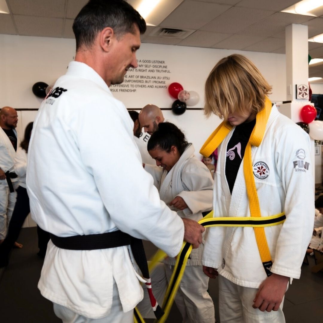 Two children grappling on a mat, one in a headlock.