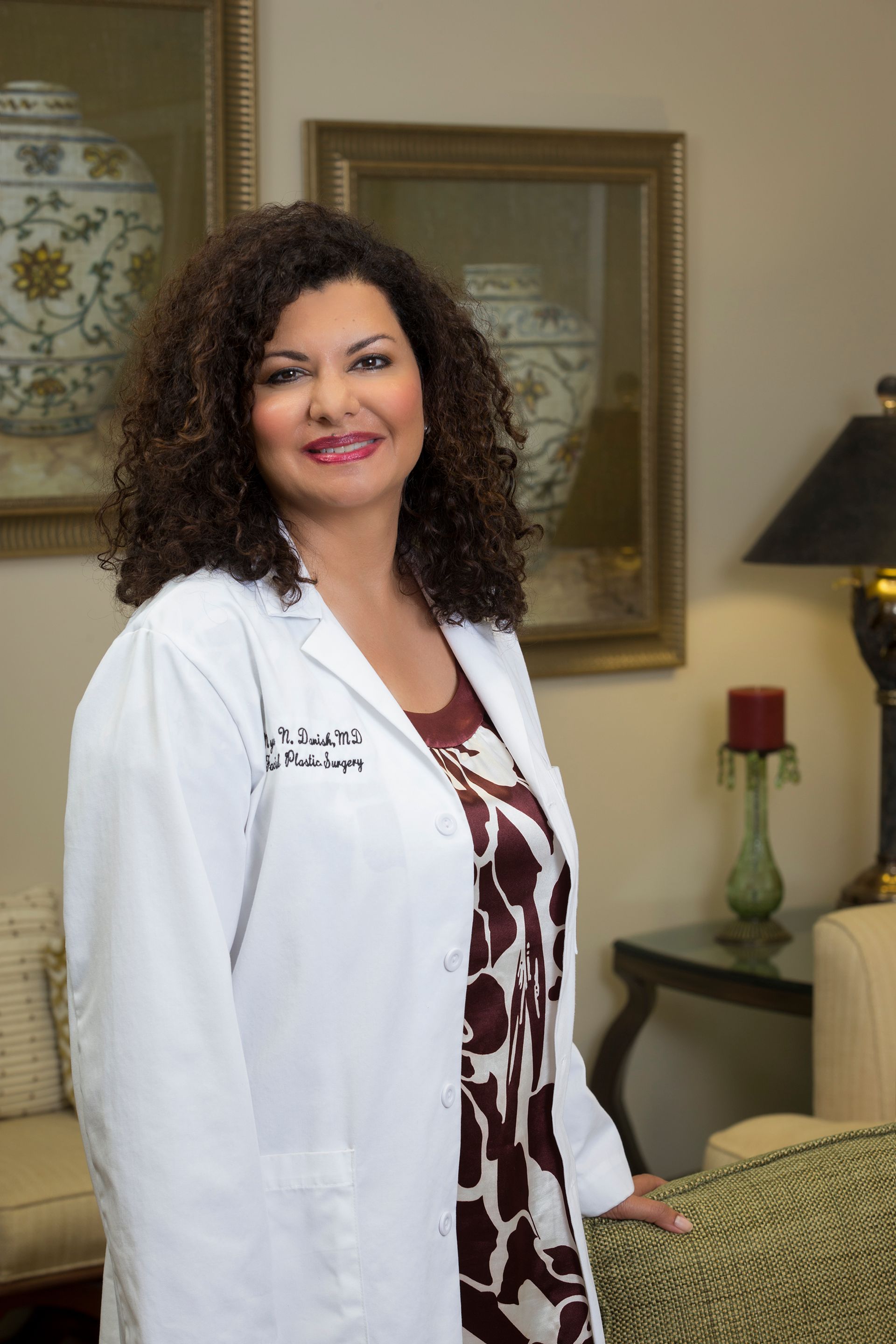 Woman with dark wavy hair and subtle makeup, looking away.