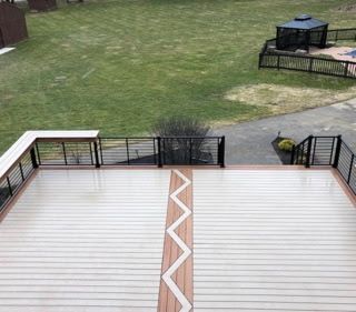 Backyard deck with white railing and zigzag center trim overlooking a grassy yard
