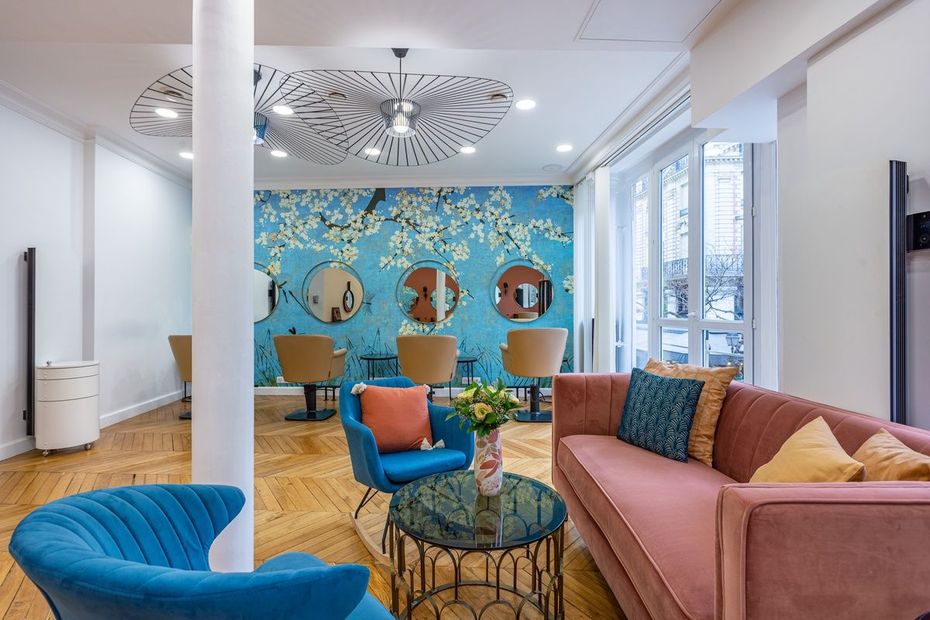 Intérieur de salon avec décor bleu et rose ; miroirs, chaises et canapé.