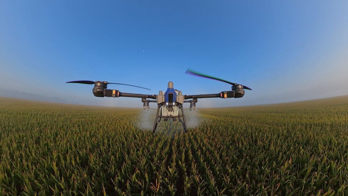 Drone on a dirt surface with blades extended, ready for flight.