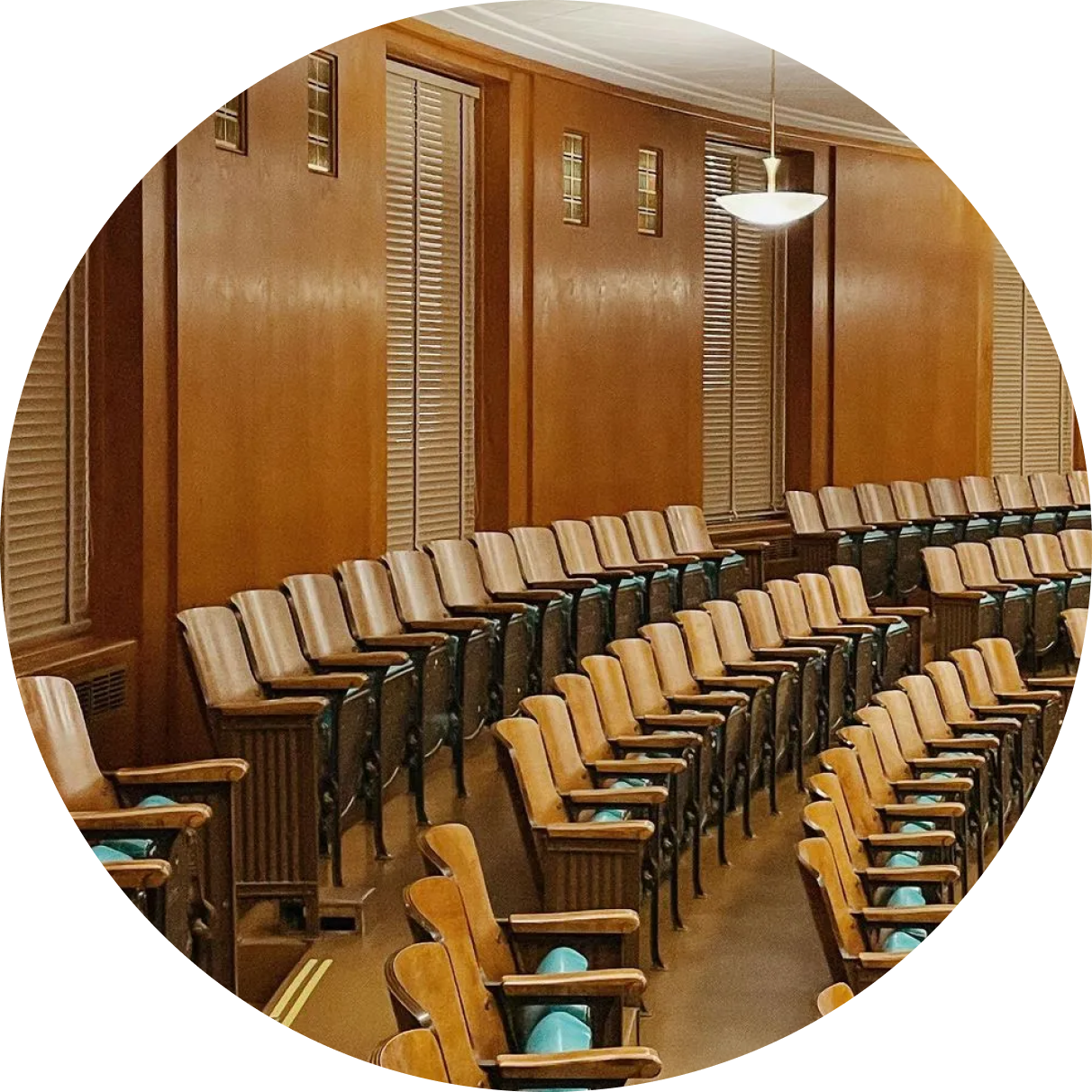 Rows of wooden chairs are lined up in an auditorium