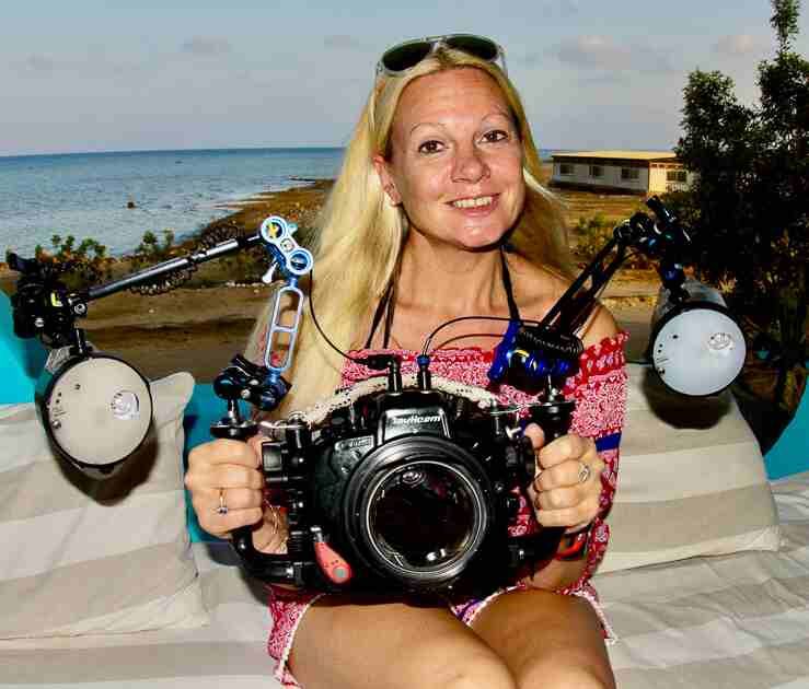 A lady with blonde hair holding a large underwater photography camera known as the Fiji underwater photographer