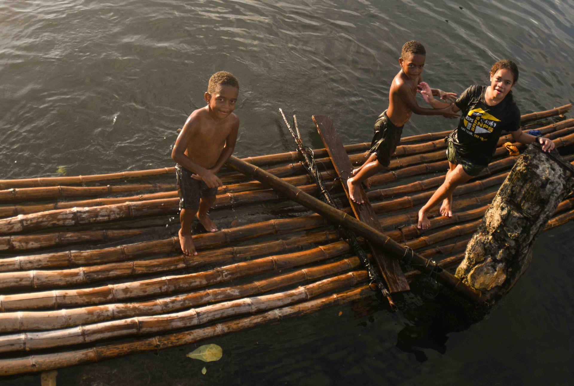 Children playing on a bamboo raft in the authentic Fiji of Savusavu town 