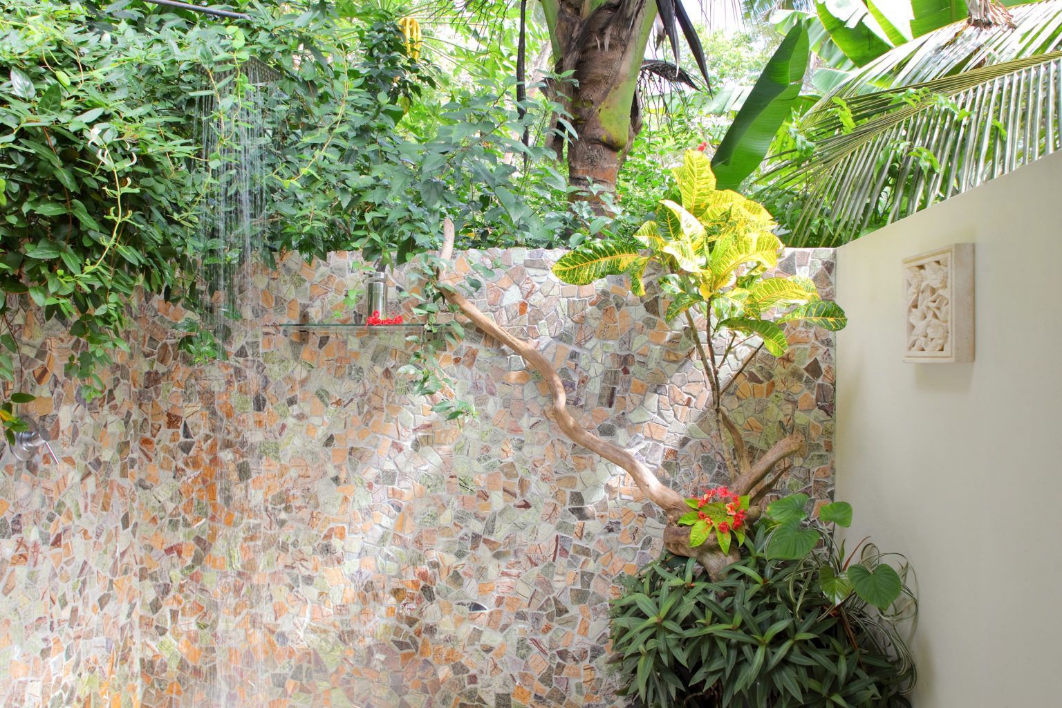 The outdoor shower area complete with a decorative stone wall and plants at Sau Bay Resort in Fiji 
