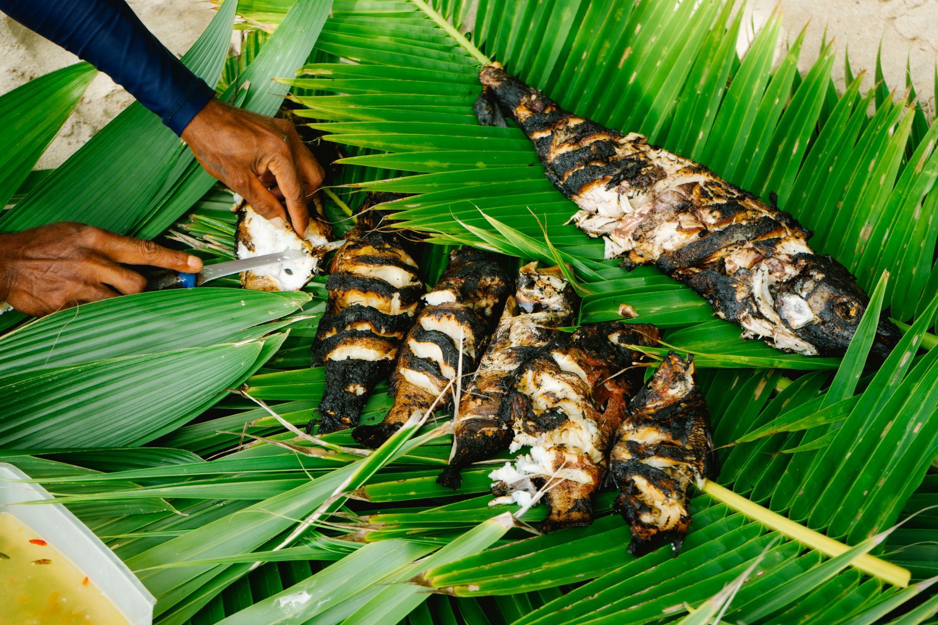 A traditional Fijian lovo of fish kebabs being cooked in banana leaves