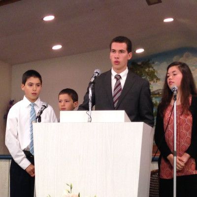 Four people stand behind a white podium with microphones in a meeting room.