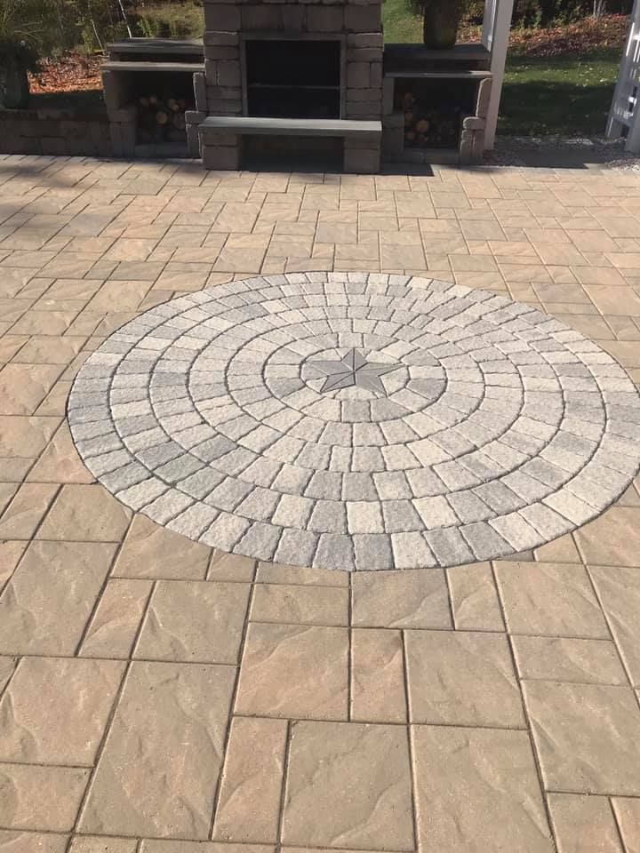 Outdoor patio with a circular stone design and fireplace in the background.