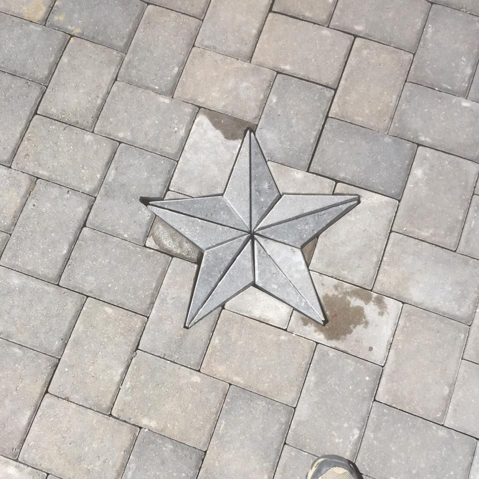 Star-shaped paving stone on a gray brick patio.