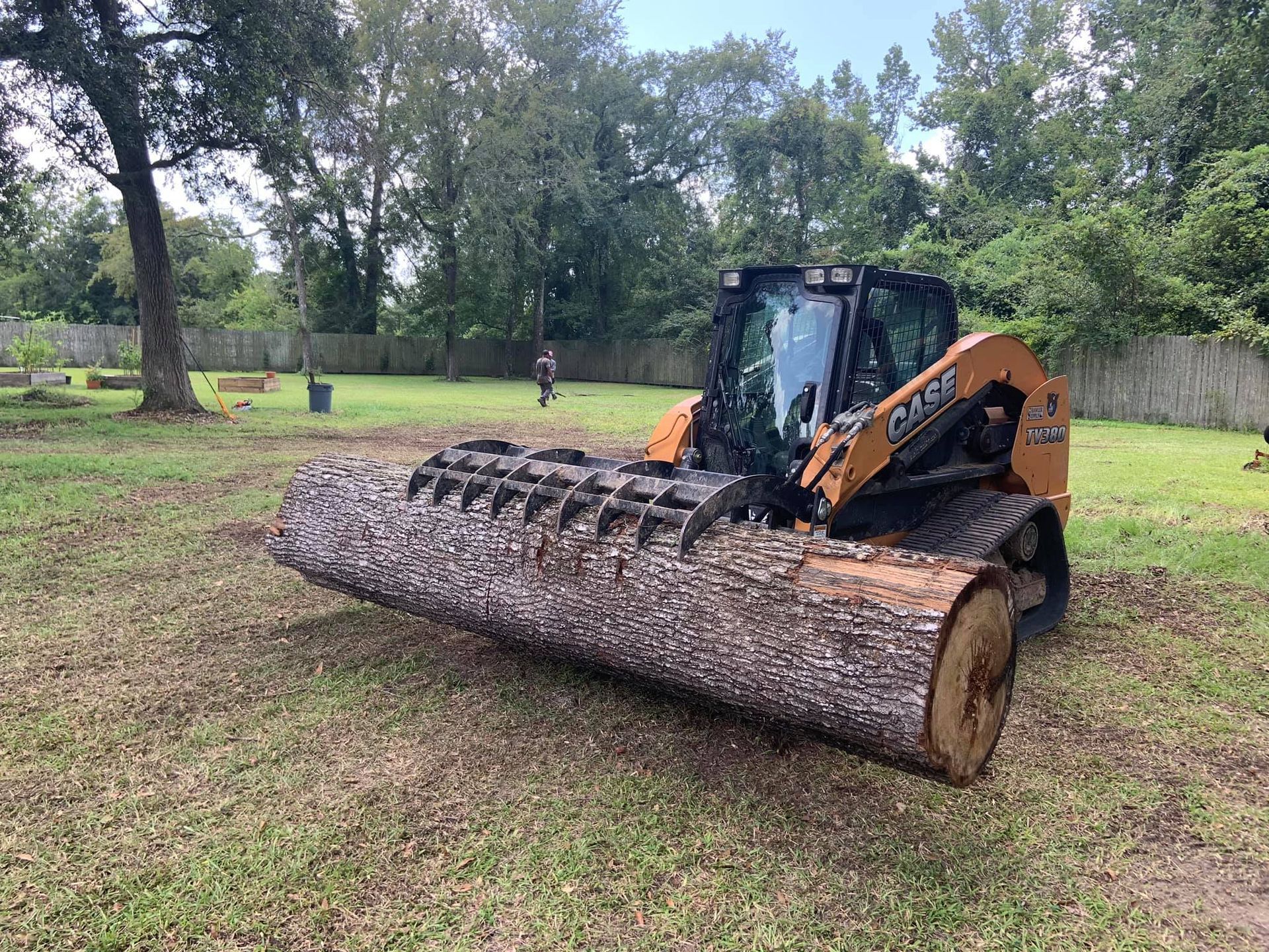 A tractor is carrying a large log in a field.