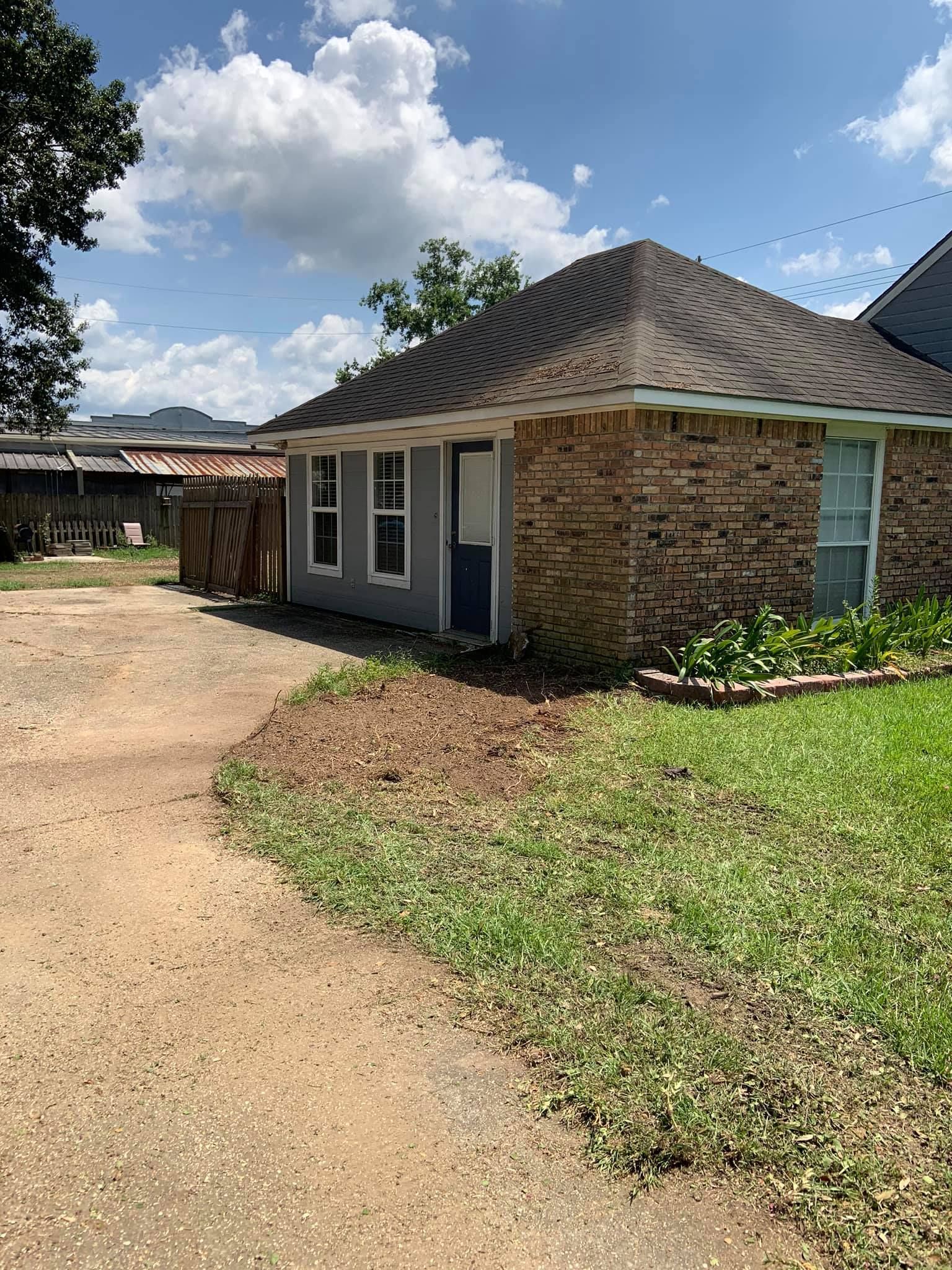 A brick house with a blue door and a driveway in front of it.