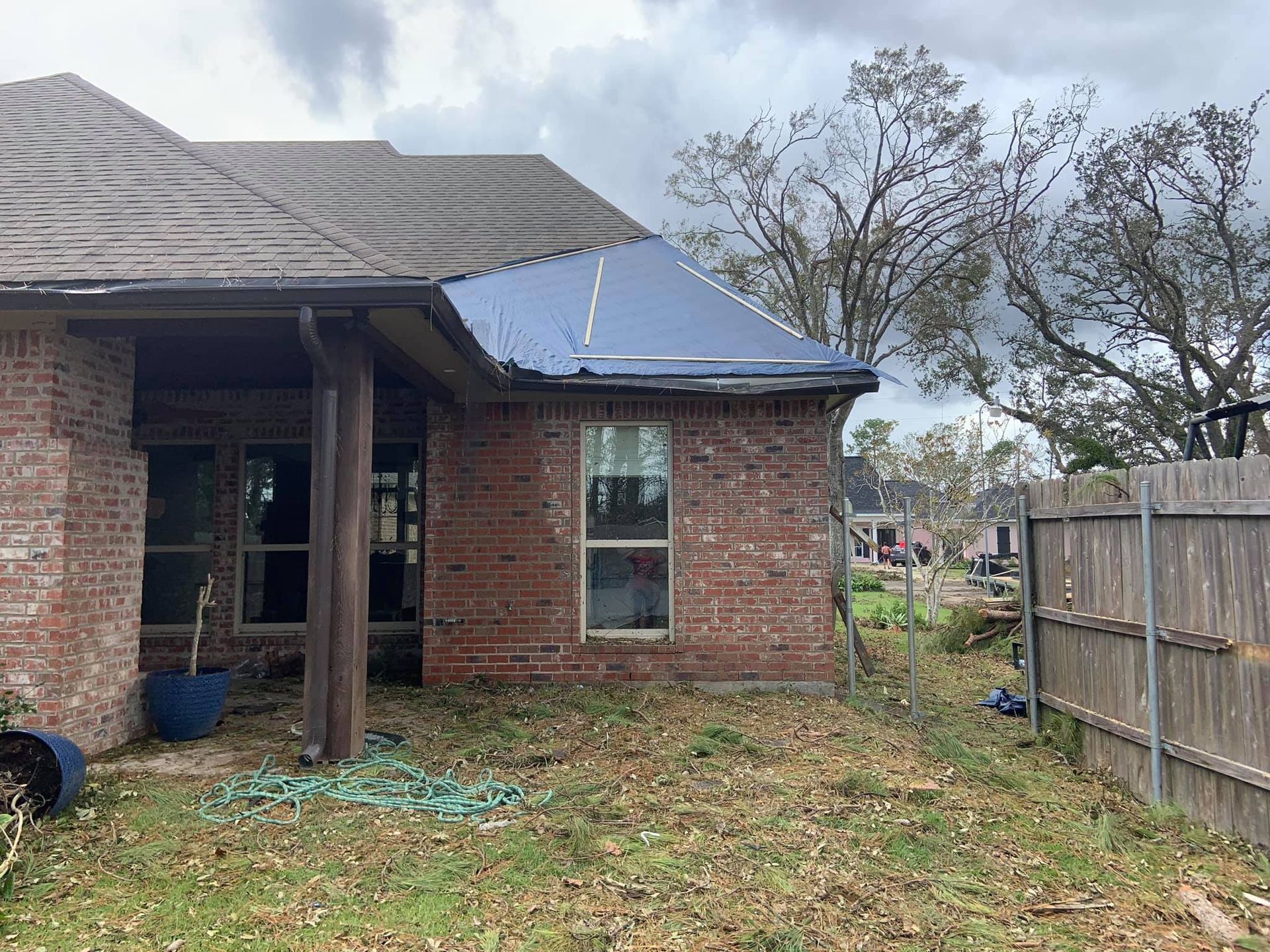 A brick house with a tarp on the roof.