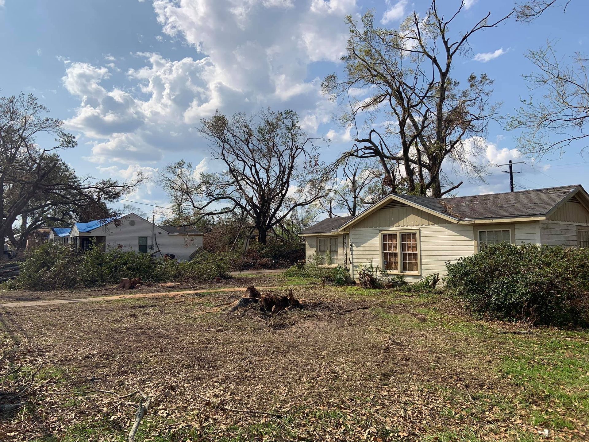 A white house is sitting in the middle of a field surrounded by trees.