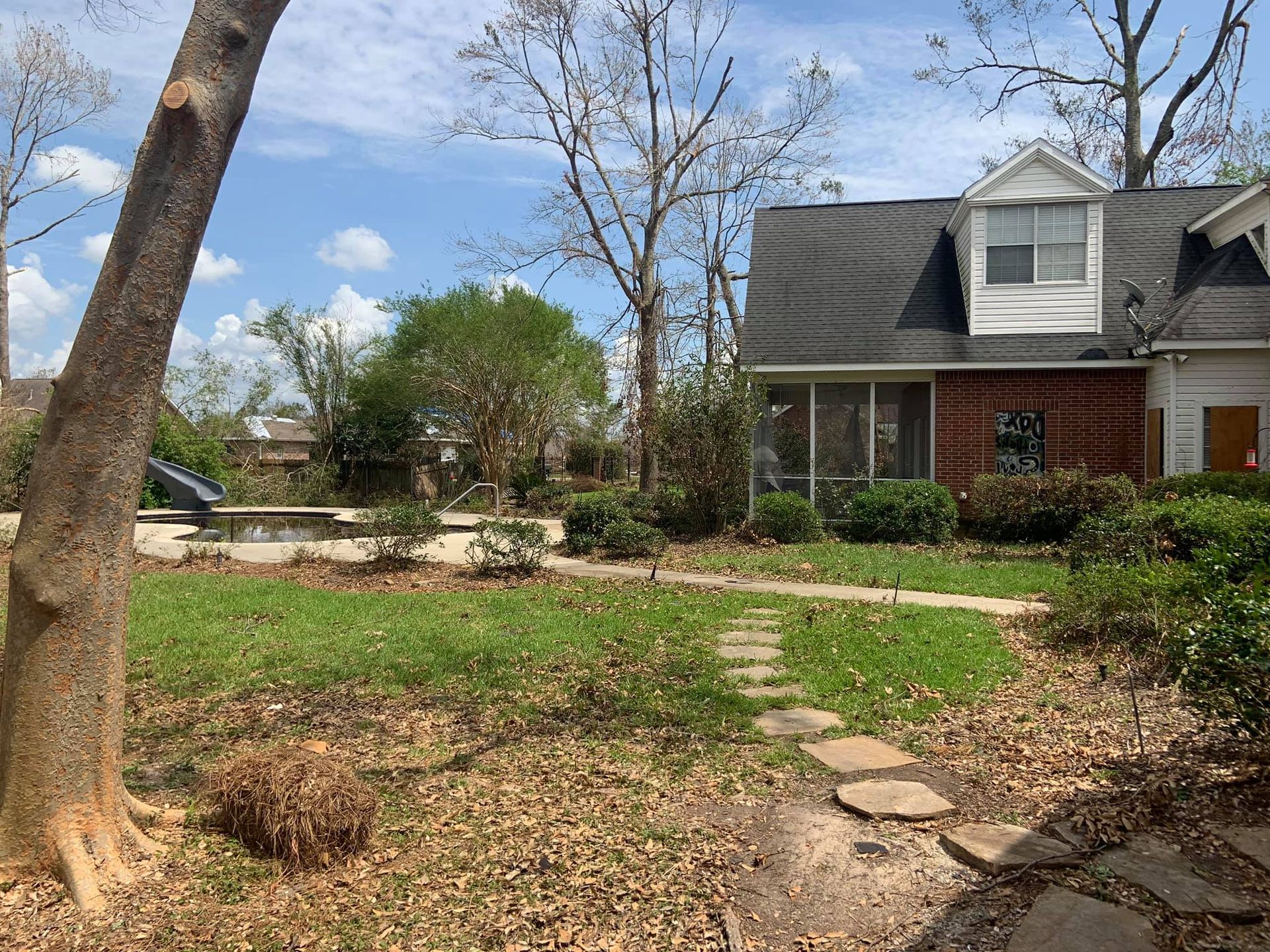 A house with a tree in front of it and a path leading to it.