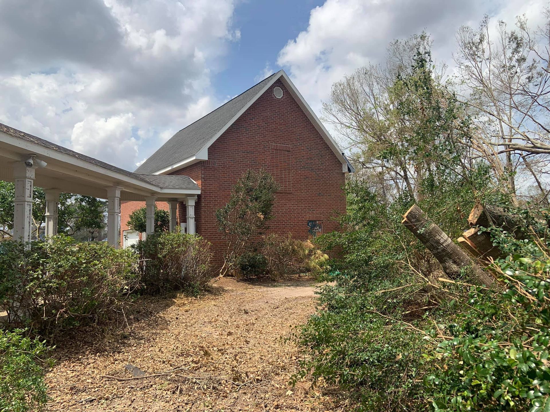 A brick house with a porch and a lot of trees in front of it.