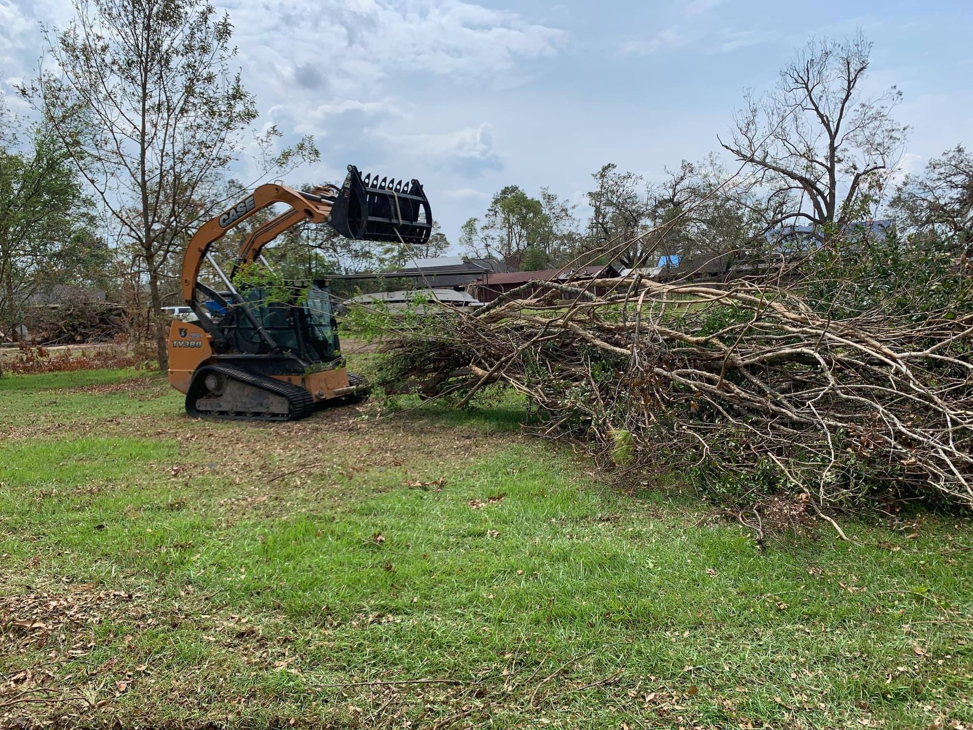 A bulldozer is moving a pile of branches in a field.