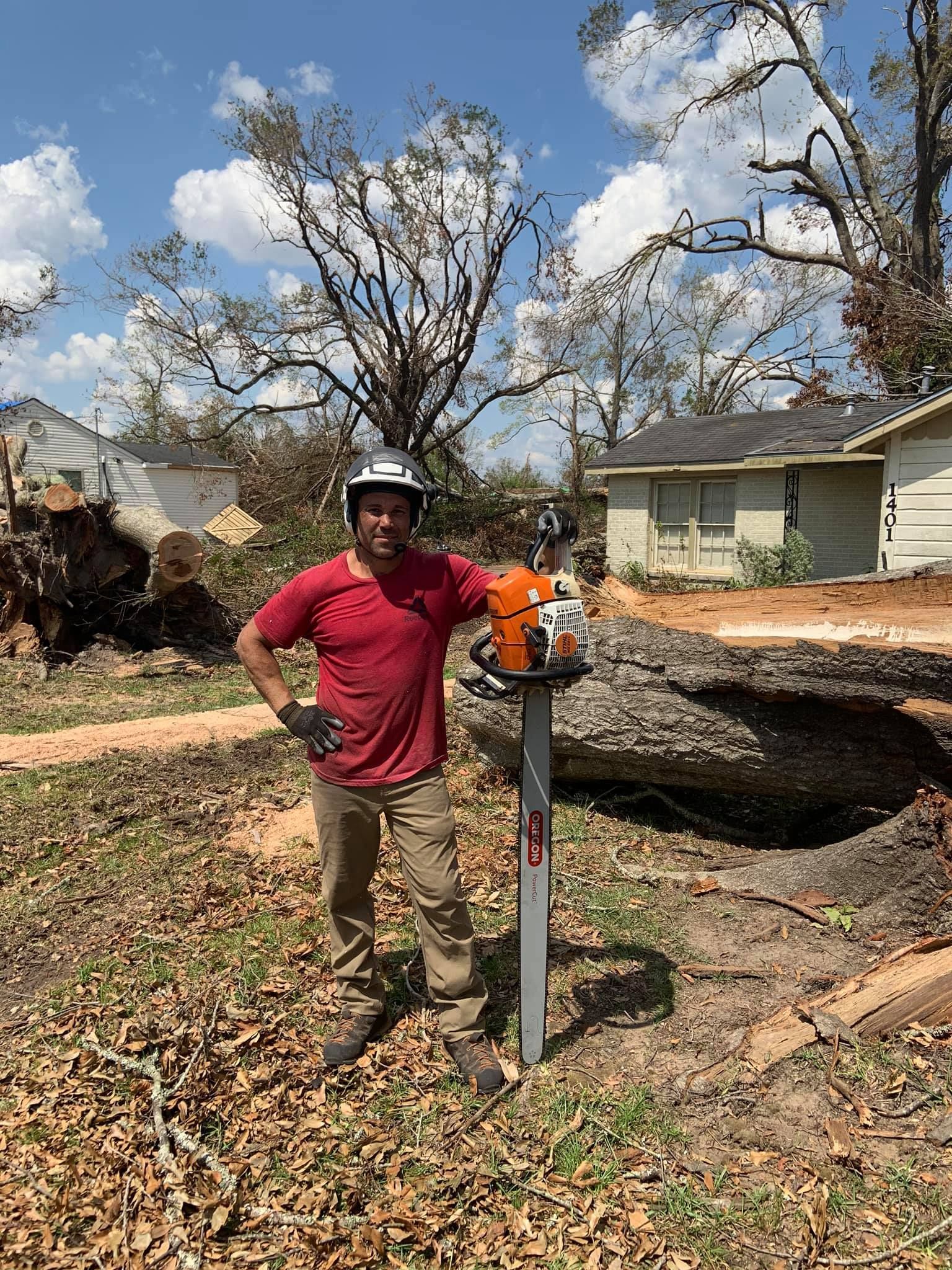 A man is standing next to a chainsaw in a yard.