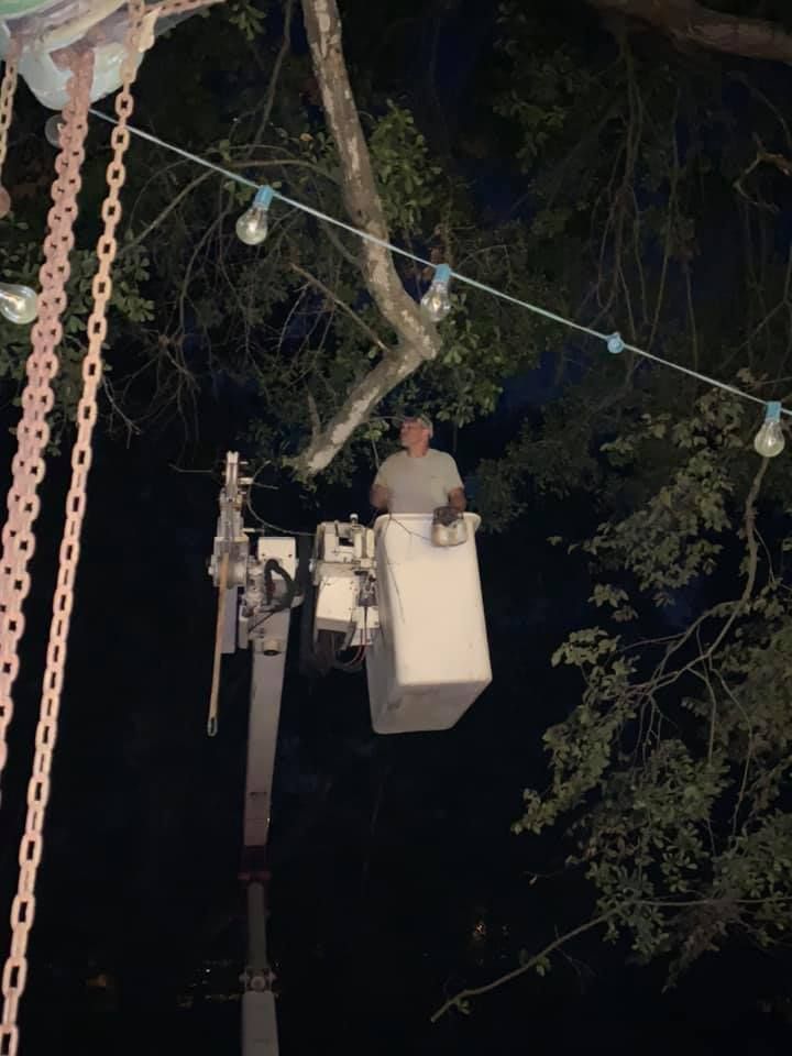 A man is sitting in a bucket on a crane at night.