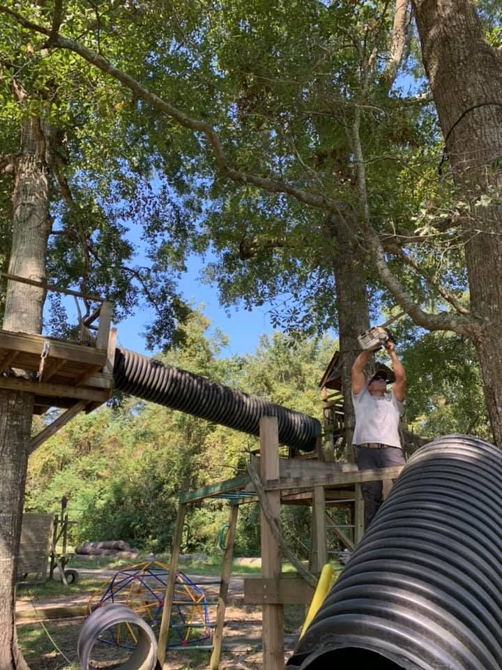 A man is standing on top of a wooden structure in the woods.