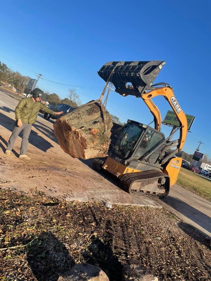 A man is standing next to a bulldozer carrying a large rock.