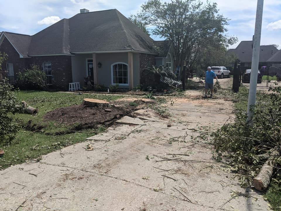 A man is standing in front of a house that has been damaged by a tornado.