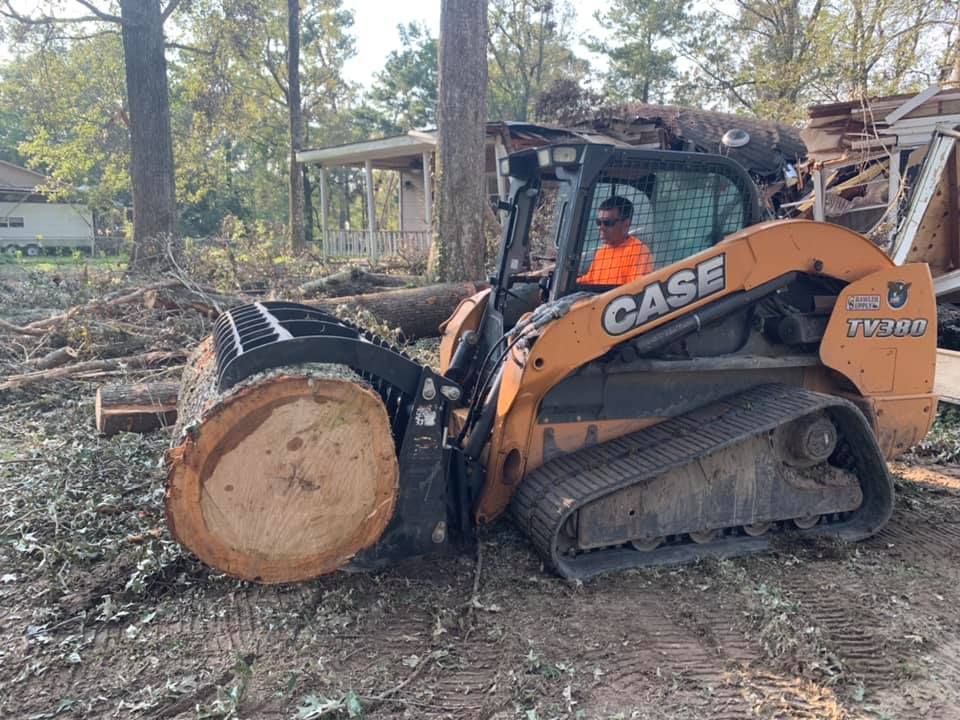 A man is driving a case tractor carrying a large log.