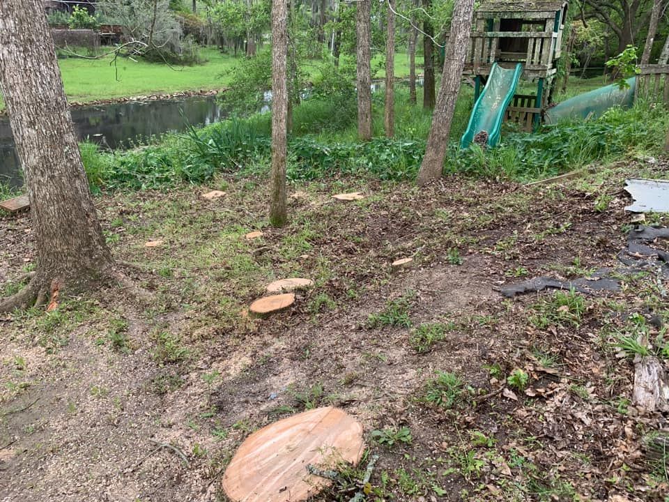 A tree stump is sitting in the middle of a yard next to a playground.