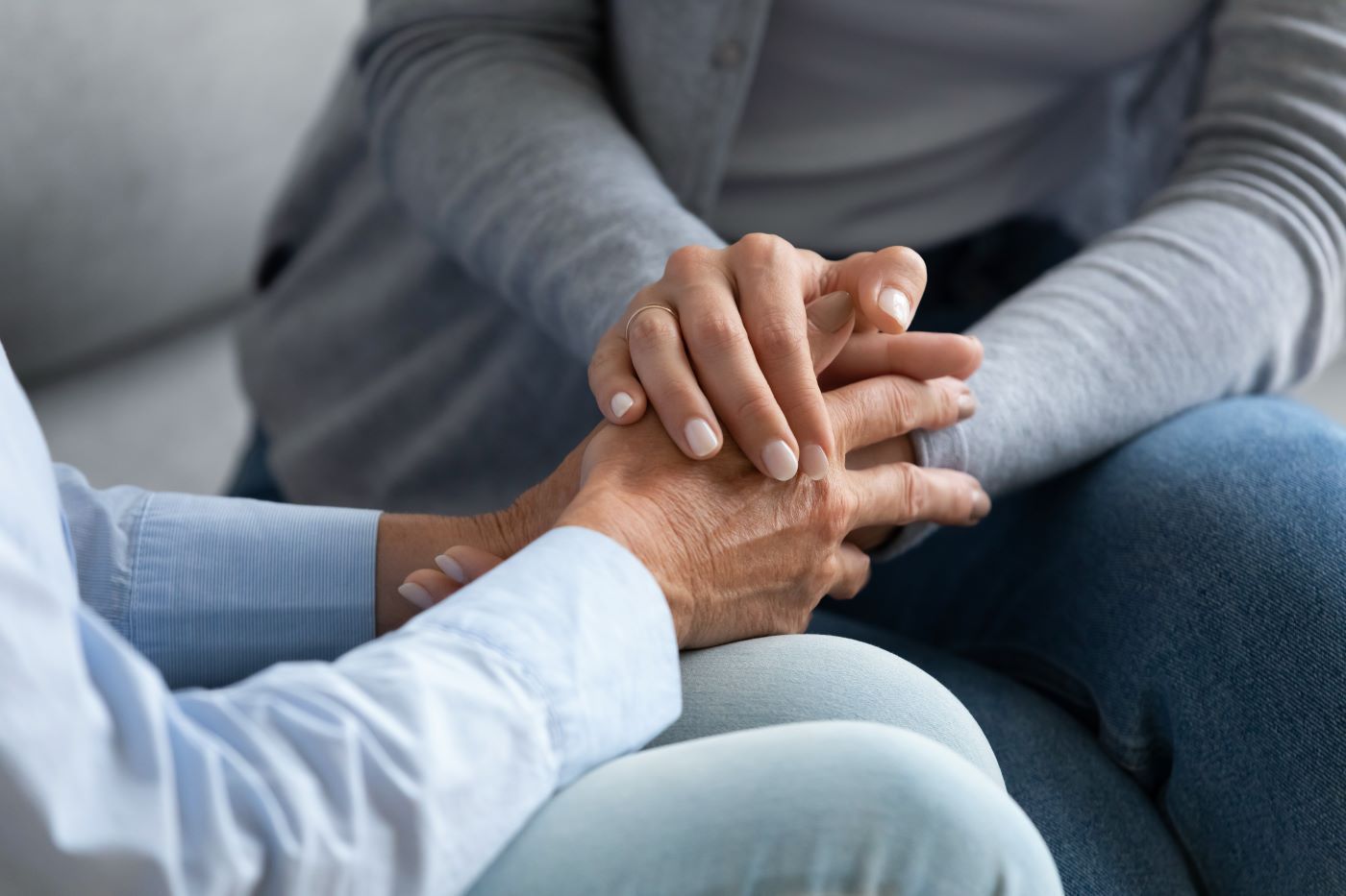 A man and a woman are holding hands while sitting on a couch.