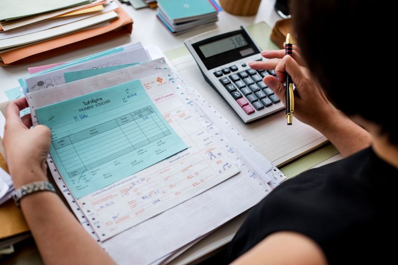 Person filling out a form beside a calculator and notebook at a desk