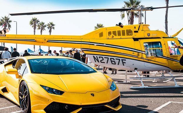 A yellow lamborghini is parked next to a yellow helicopter in a parking lot.